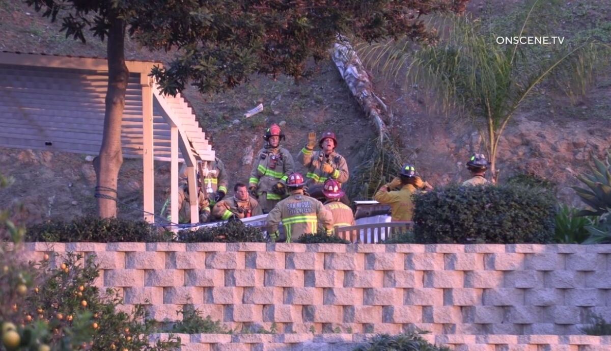 Emergency crews from San Miguel Fire & Rescue surround an overturned car that landed in the back patio area of a home on La Cruz Place.