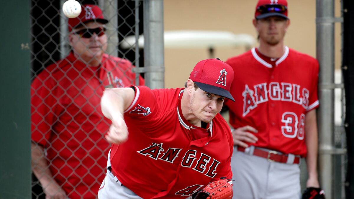 Angels starter Garrett Richards throws during a bullpen session as Manager Mike Scioscia and teammate Jered Waver watch on Feb. 19.