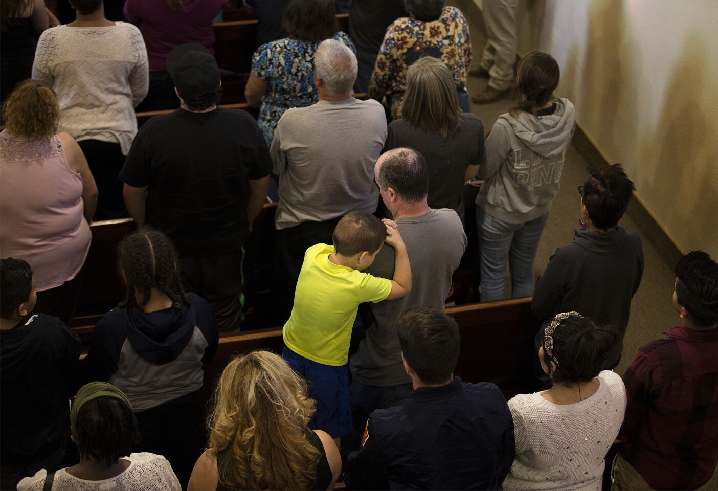 A child rests his head on his father's shoulder during a prayer service at Our Lady of Assumption Catholic Church for the victims in the shooting at North Park Elementary School.