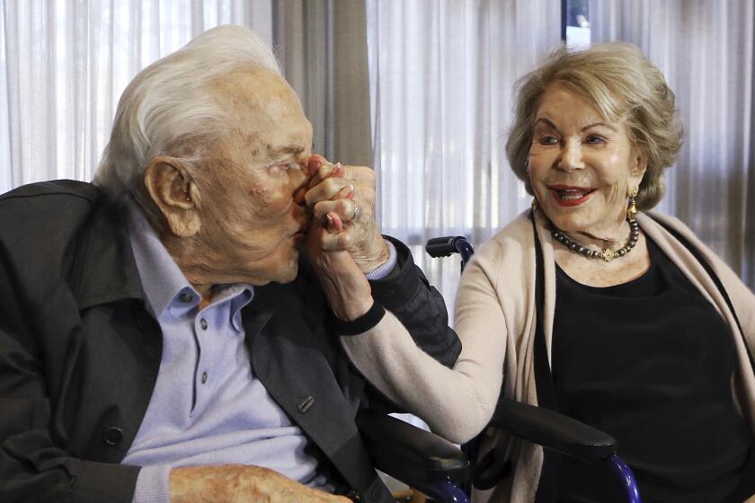 In this May 4, 2017, file photo, Kirk Douglas kisses his wife Anne's hand during a party celebrating his 100th birthday.
