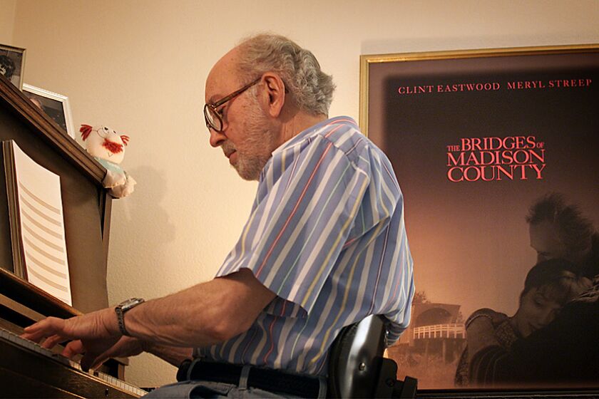 Ricardo DeAratanha –– – Thursday, 8/10/2000, Thousand Oaks, CA – DIGITAL IMAGE – Lennie Niehaus (cq) at his piano with "The Bridges of Madison County" film poster on the wall. He composes music for movies. He's done some Clint Eastwood films including the one in the poster and new release "Space Cowboys."