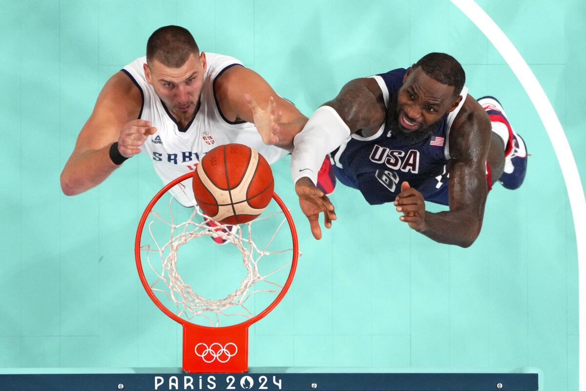 LeBron James and Nikola Jokic  reach for a rebound from a birds-eye view