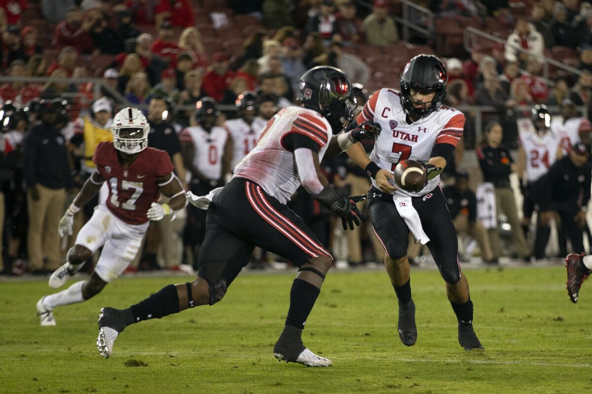 Utah quarterback Cameron Rising (7) hands off to running back Tavion Thomas during the second quarter of the team's NCAA college football game against Stanford, Friday, Nov. 5, 2021, in Stanford, Calif. (AP Photo/D. Ross Cameron)