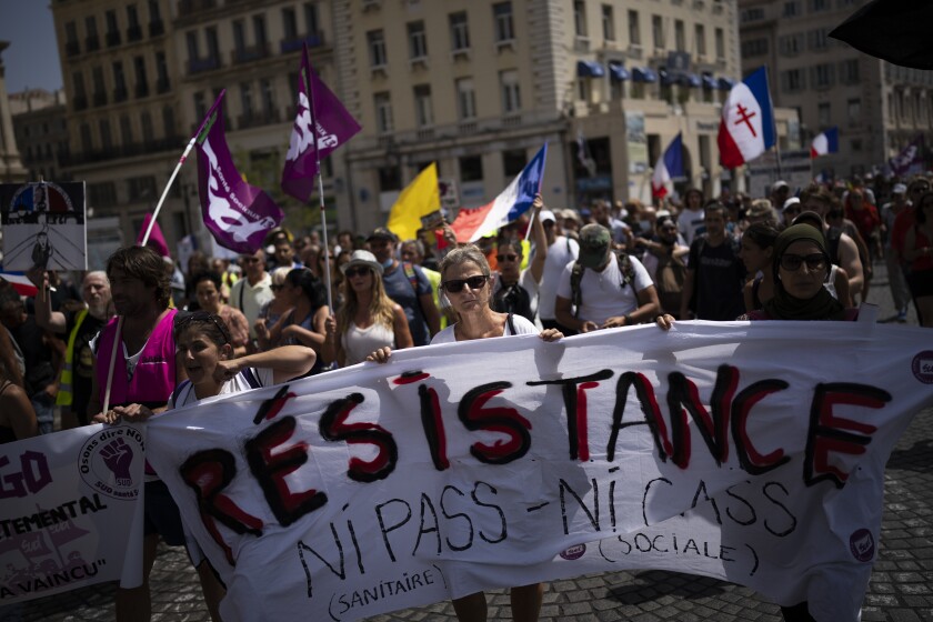 FILE - Protesters march during a demonstration to denounce a COVID-19 health pass needed to access restaurant, long-distance trains and other venues. in Marseille, southern France, Saturday, Aug. 14, 2021. The run-up to the April election comes in a context of mounting violence targeting elected officials in France, with holders of public officers targeted for their politics and by opponents of COVID-19 vaccinations restrictions. (AP Photo/Daniel Cole, File)