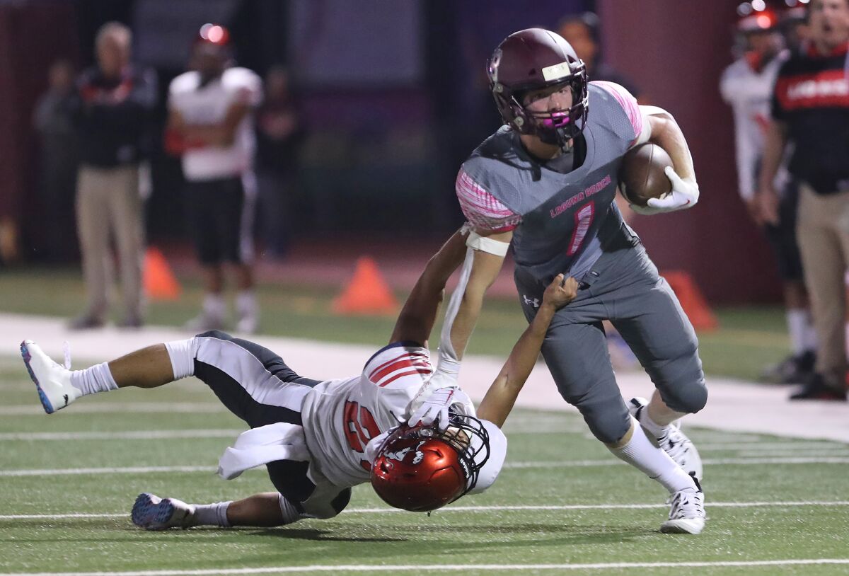 Laguna Beach's Nick Rogers (1) fights off a tackle for a big gain during a Pac 4 League football game against Westminster.