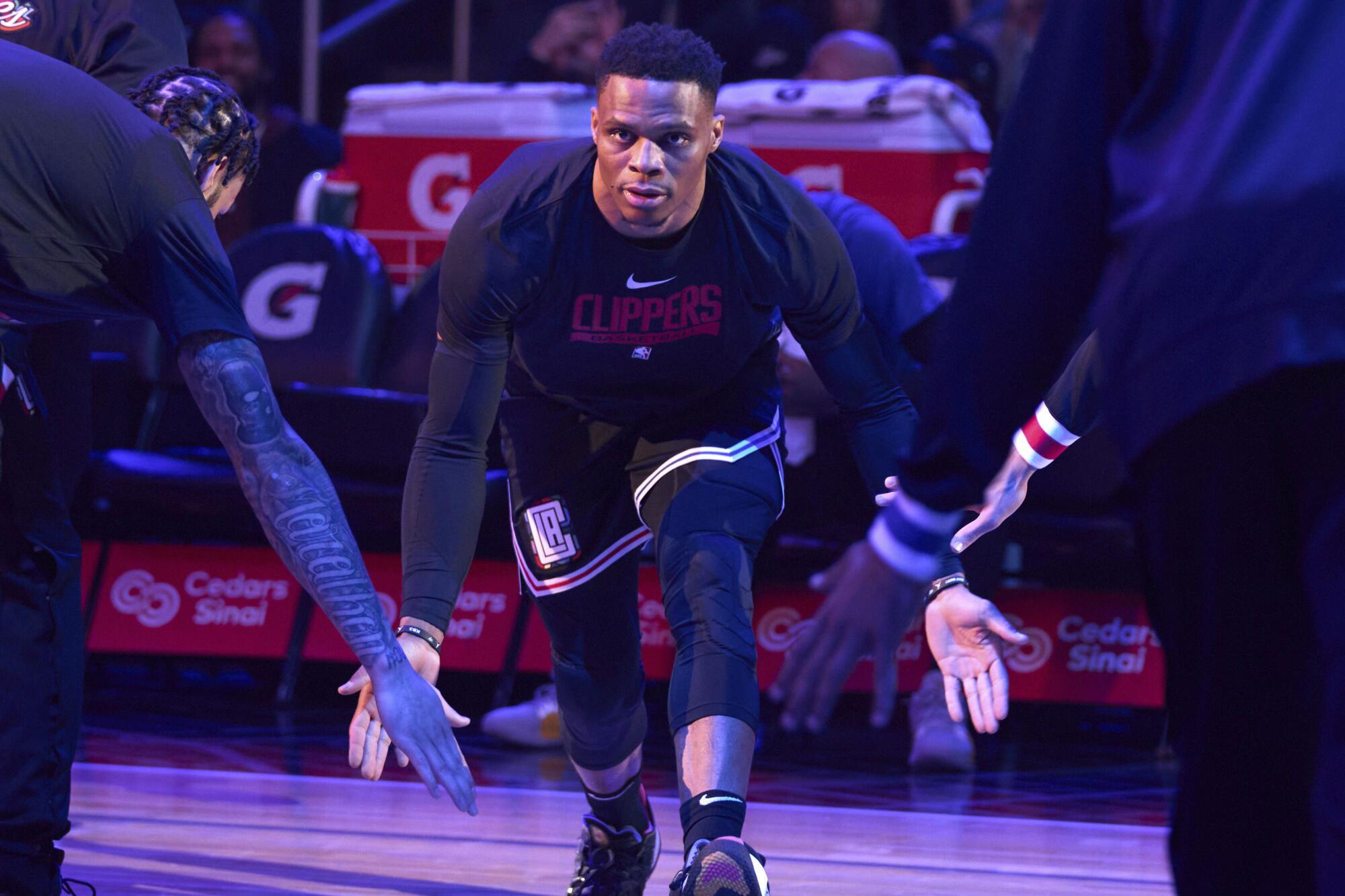 Clippers point guard Russell Westbrook slaps hands with teammates as he takes the court during player introductions.