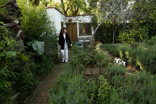 After six months of searching for a home in the Hollywood Hills, Priscilla Woolworth put in an offer on a lush Spanish-style compound within hours of touring a property — in Valley Glen. "The Mediterranean architecture, the garden and the indoor-outdoor living space reminded me of my childhood in the South of France," Woolworth says, pouring water into a flea market glass. "I was looking for a home with soul." That was in 2002, and since then, Woolworth has expanded the property to a full-fledged compound. With a converted garage and two additional bedroom suites, both freestanding cottages, the property now consists of four bedrooms and five bathrooms spread in four structures. The threads running through all of the spaces: flea market chic, a celebration of color and a love of the natural world. Here, Woolworth walks among beds of lavender with a guest house behind her. Read the full story on Priscilla Woolworth's home .