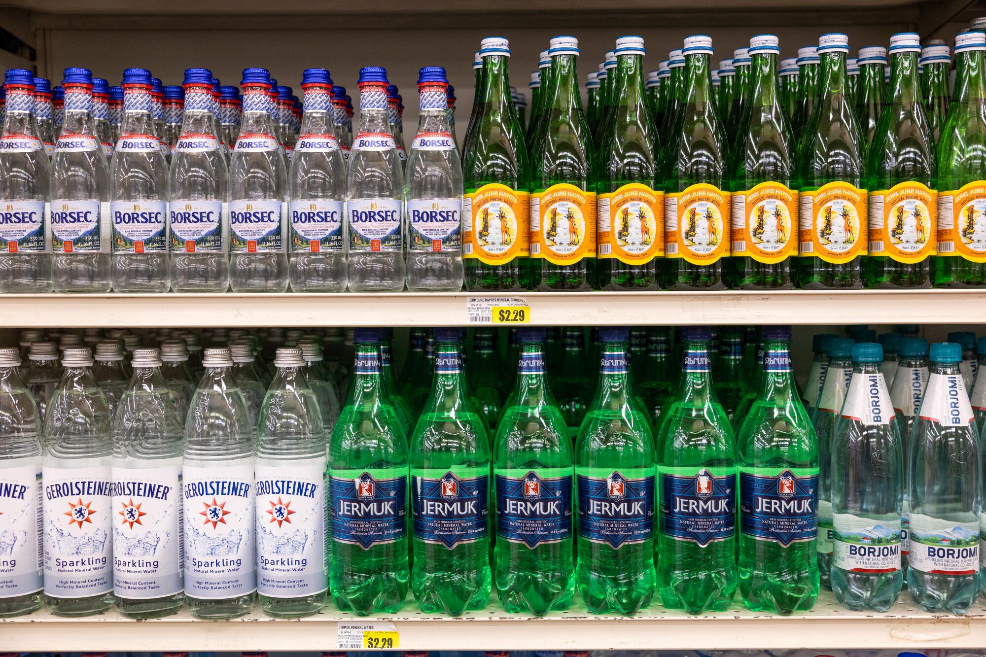 Assorted bottles of mineral water in sections on two shelves