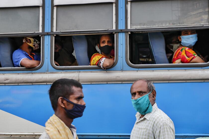 Commuters wearing face masks to prevent coronavirus wait inside a bus in Kolkata, India.