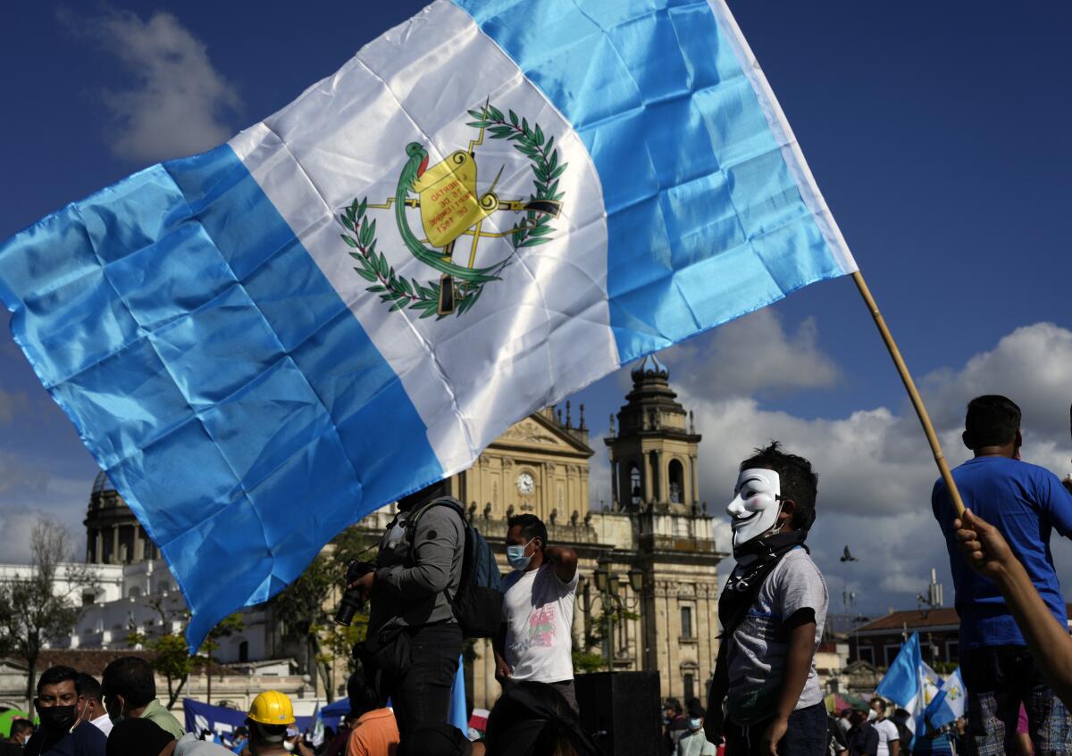 A child wearing a Guy Fawkes' mask often linked to popular movements stands on a stage during a rally to pressure Guatemalan President Alejandro Giammattei to resign, in Guatemala City, Saturday, July 31, 2021. The protest comes in response to the firing of Special Prosecutor Against Impunity Juan Francisco Sandoval by Attorney General Consuelo Porras. (AP Photo/Moises Castillo)