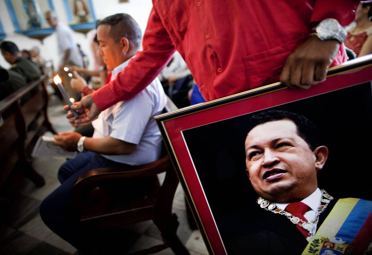 A Venezuelan Embassy staffer holds a picture of President Hugo Chavez at a service devoted to the sick in Regla, Cuba. The Venezuelan leader is recovering from surgery in Cuba.