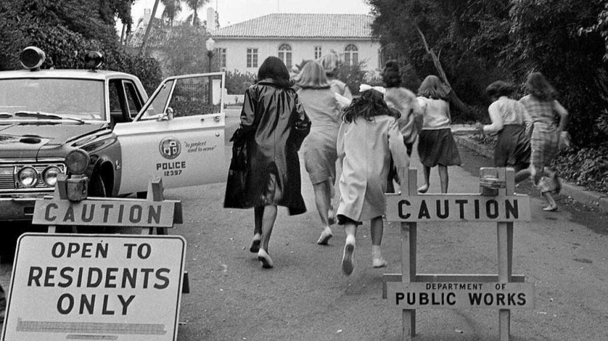 Aug. 25, 1964: Beatle fans run pass barricades and rush policemen in effort to reach the Bel-Air home where the band was staying. The fans were stopped before reaching the band.