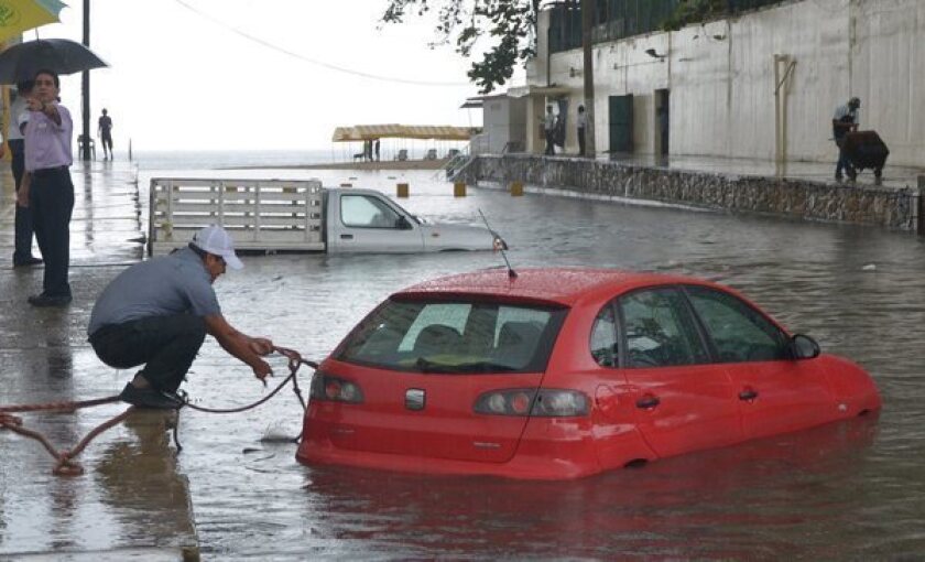 A man tries to rescue his stranded vehicle in the Pacific port of Acapulco, in Guerrero, Mexico