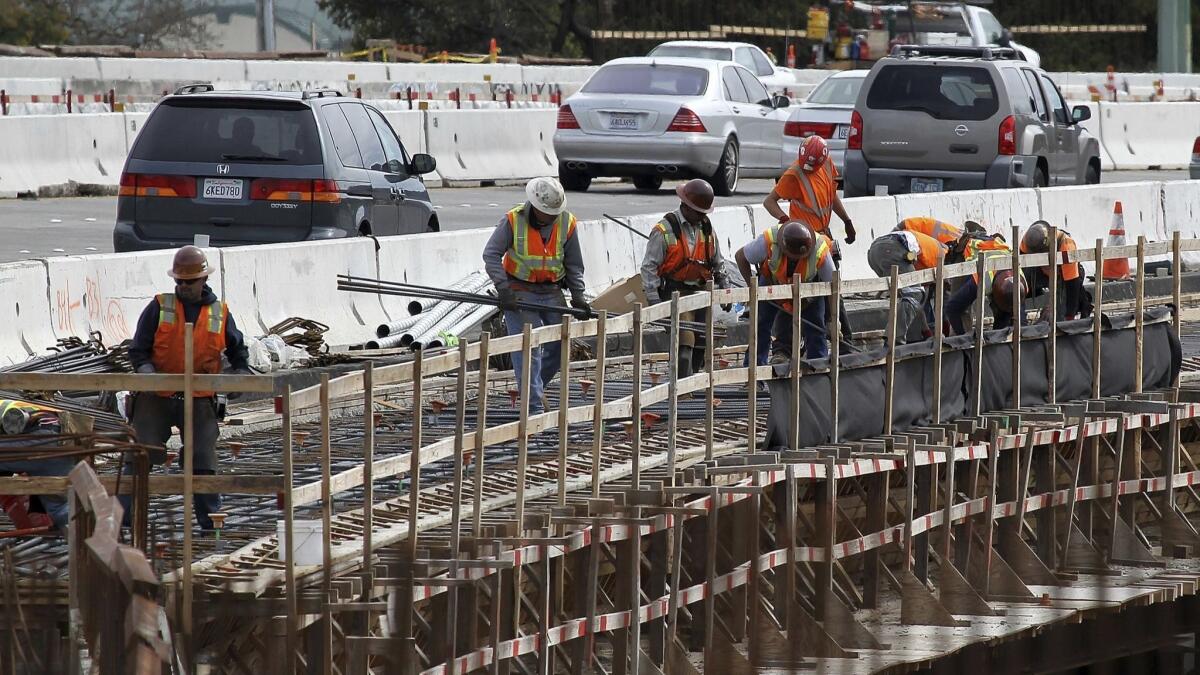 Construction crews work on a freeway overpass along Highway 101 in Novato, California.