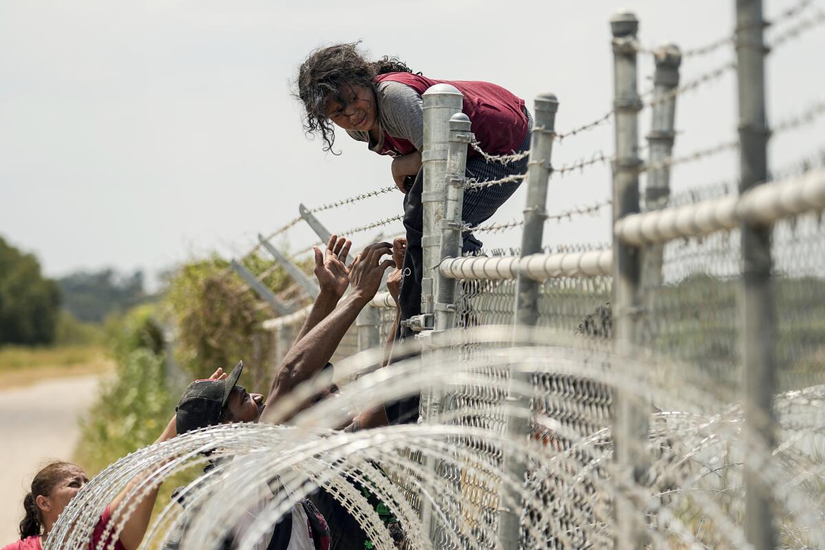 Migrants climb a border fence into Eagle Pass, Texas.