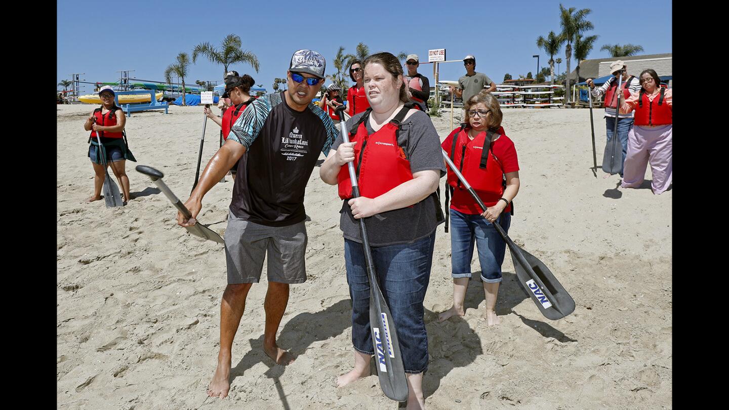 Elizabeth Sonne of Laguna Beach is led to an outrigger canoe by R.J. De Rama of the Makapo Aquatics Project during a Project Independence Access 2 Adventure activity Wednesday at the Newport Aquatic Center.