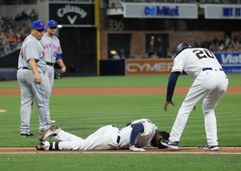 Padres' Jemile Weeks lays on the first base path after get in tagged out trying to get to first. Assisting him is 1st. base coach Tarrik Brock.