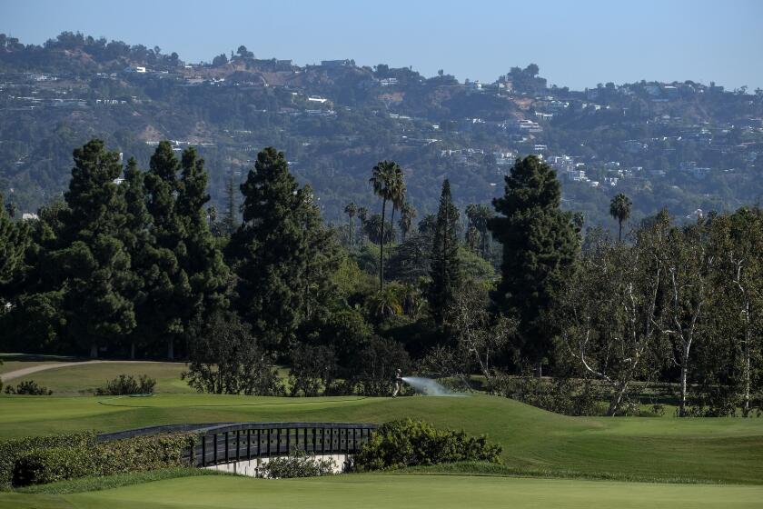 A worker waters the 16th hole during the First Look for the U.S. Open Championship.