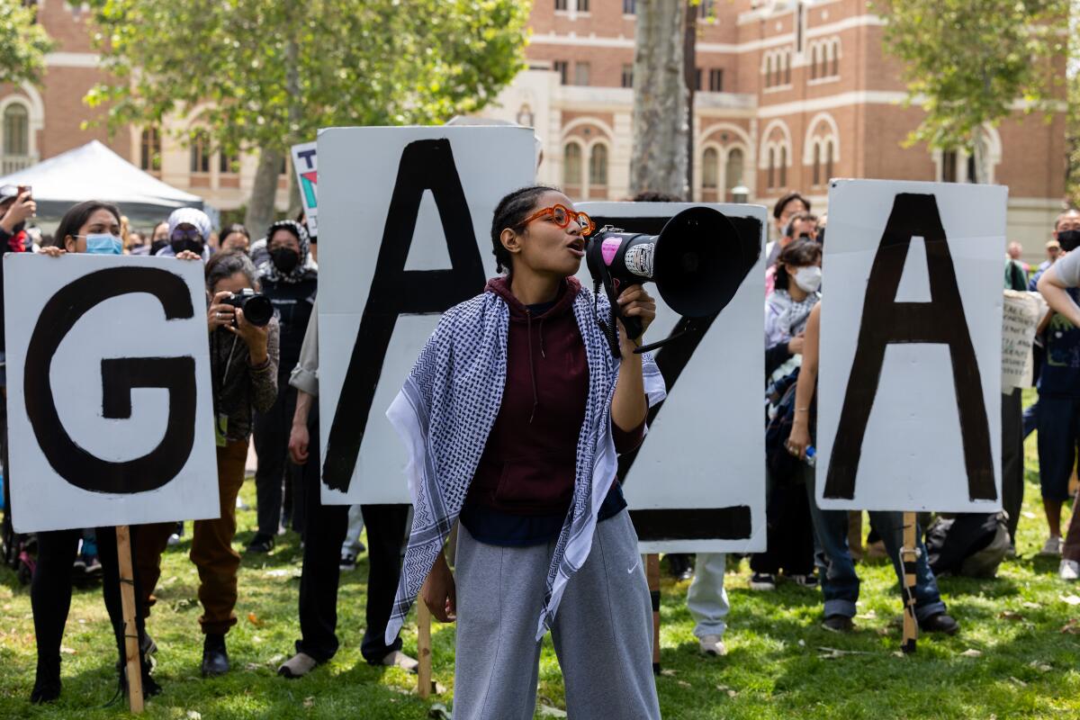 A woman speaking through a bullhorn in front of a Gaza sign. 
