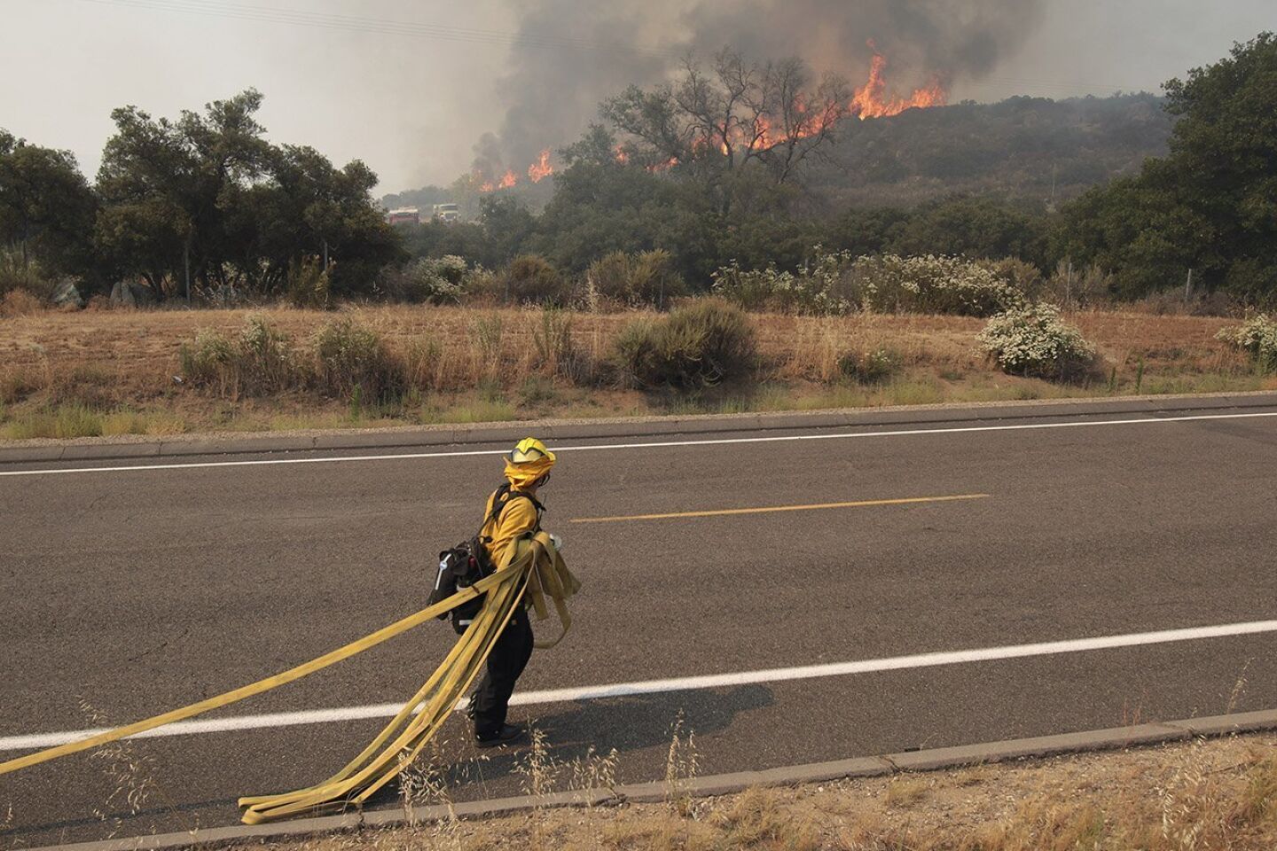 A firefighter pulls out a hose as a wildfire approaches Highway 94 near Potrero on Monday.
