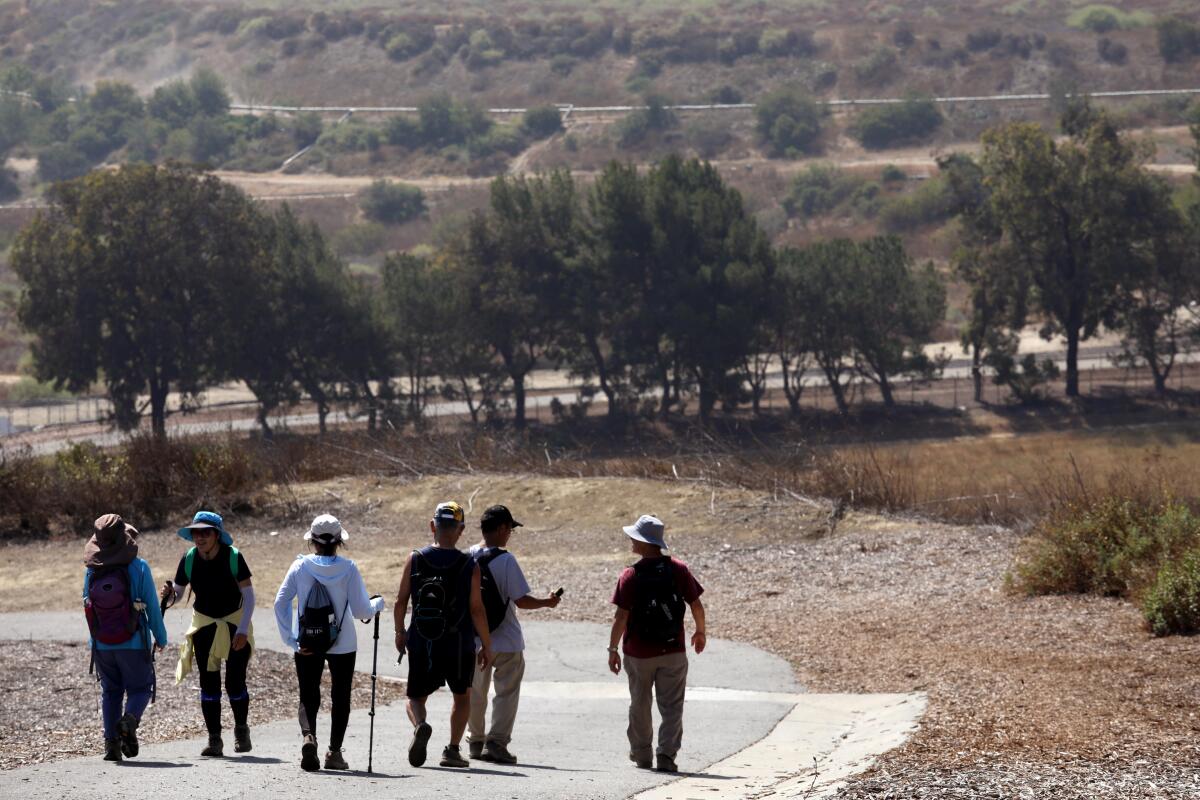 Six people hike along a paved trail.