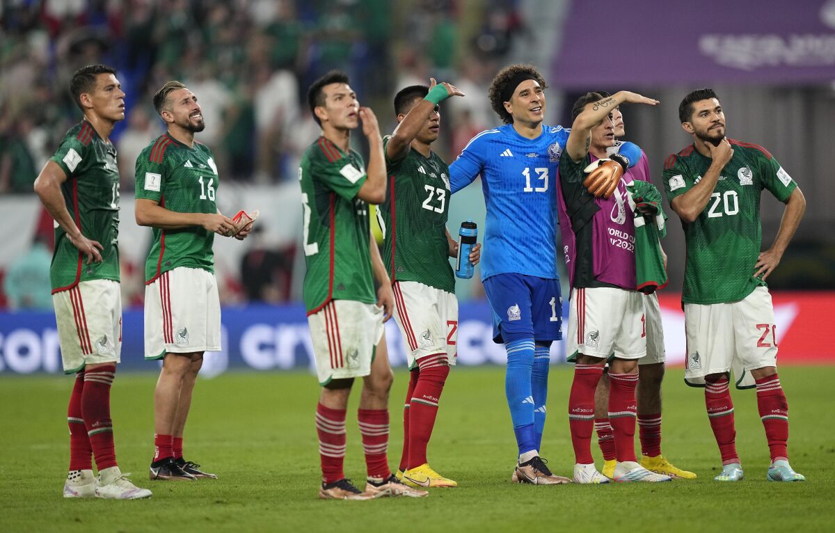 Mexico goalkeeper Memo Ochoa stands with teammates on the pitch after a draw with Poland