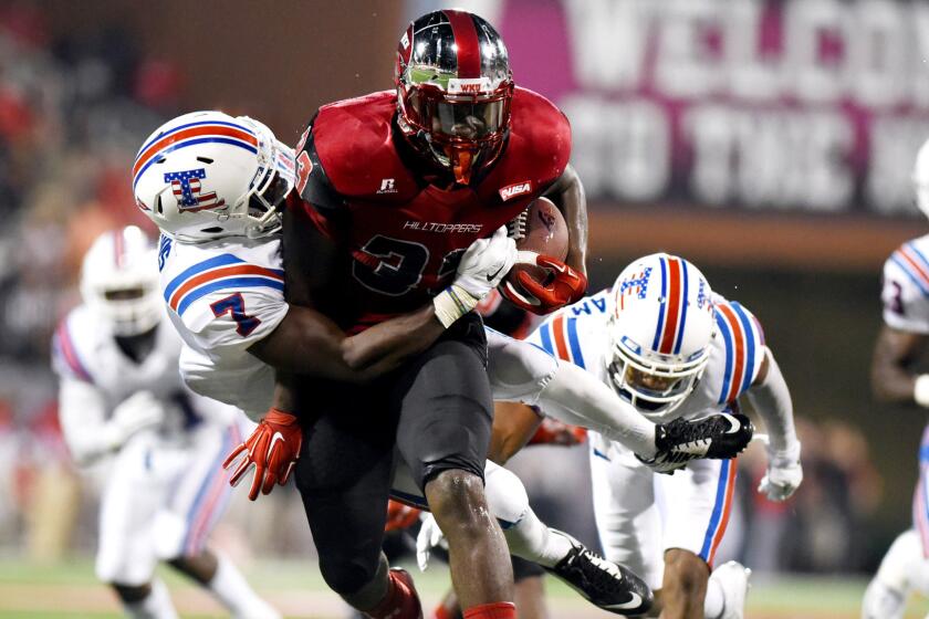 Western Kentucky running back Kenneth Dixonm who rushed for 168 yards and two touchdowns, is brought down by Louisiana Tech defensive back Xavier Woods on Thursday night.
