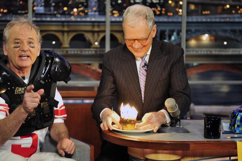 Bill Murray, left, tells the audience not to scream after lighting 30 birthday candles in a cupcake as a gift to host David Letterman for his 30 years in TV, on the set of the "Late Show with David Letterman" on Jan. 31, 2012.