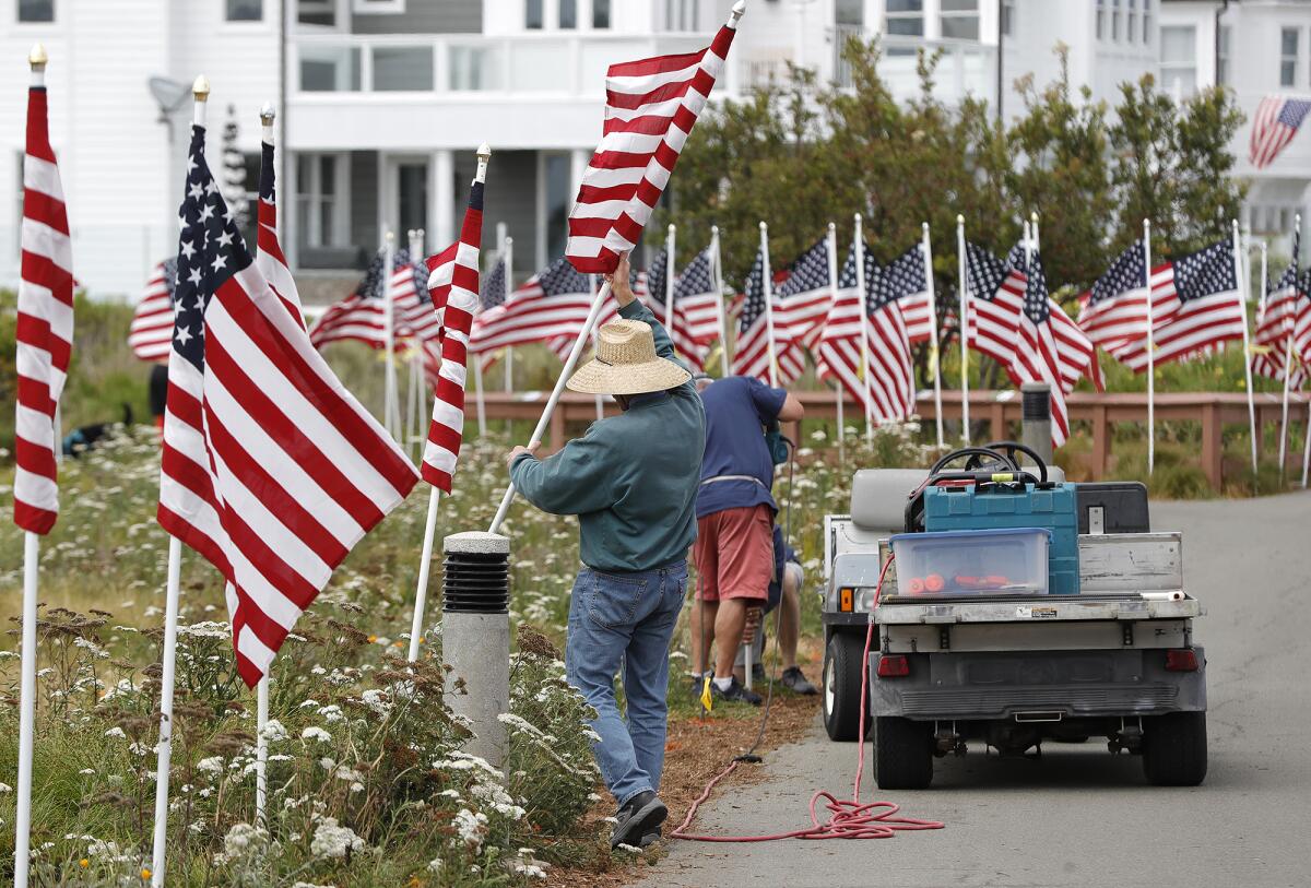 A volunteer places one of 1,776 large American flags.