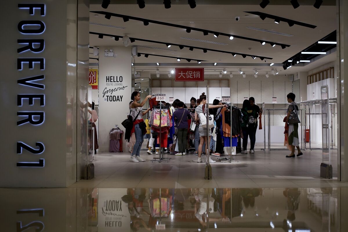 FILE - In this Tuesday, May 7, 2019, file photo, women select clothing at an American fast fashion retailer Forever 21 which is offering clearance discounts at a shopping mall after it pulled out from China's market, in Beijing. Low-price fashion chain Forever 21, a one-time hot destination for teen shoppers that fell victim of its own rapid expansion and changing consumer tastes, announced Sunday, Sept. 29, 2019, that it has filed for Chapter 11 bankruptcy protection. (AP Photo/Andy Wong, File)