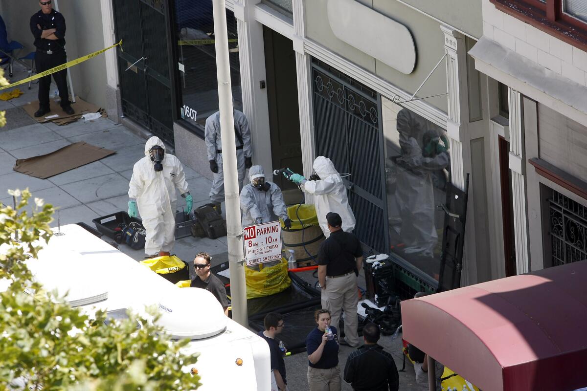 Agents in hazardous material suits search a building in San Francisco where Ryan Chamberlain II reportedly lived on Saturday.