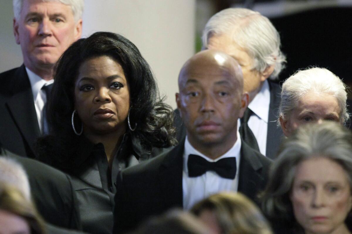 Oprah Winfrey, second from left, and Russell Simmons, center, attend the funeral of Eunice Kennedy Shriver in 2009. Winfrey will no longer produce a #MeToo documentary about Simmons premiering at Sundance this month.