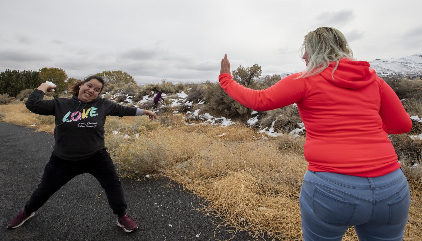 Pacoima residents Andrea Hernandez, right, lifts a hand to deflect a snowball about to be thrown by friend Maria Salazar, left, as desert snow lingers in the Antelope Valley town of Palmdale in Palmdale, Calif., on Dec. 1, 2019.