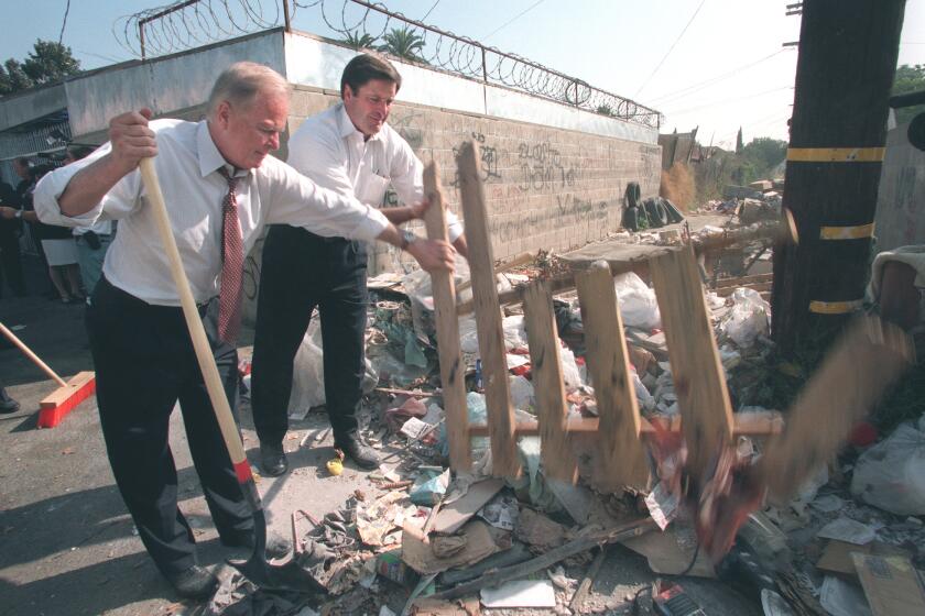 Los Angeles Mayor Richard Riordan (left) and Deputy Secretary of the United States Department of the Interior , John Garamendi (right), roll up their sleeves and pitch in to help cleanup an alley near 58th Street and Central Ave in South Los Angeles. The alley is the site of illegal dumping. Riordan and other officials were on hand to announce a city campaign against illegally dumped trash. Photo taken 9/19/96.Mandatory Credit: Anacleto Rapping/The LA Times