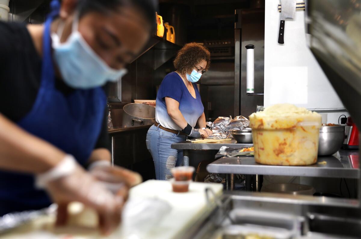 Two people making tamales in a commercial kitchen