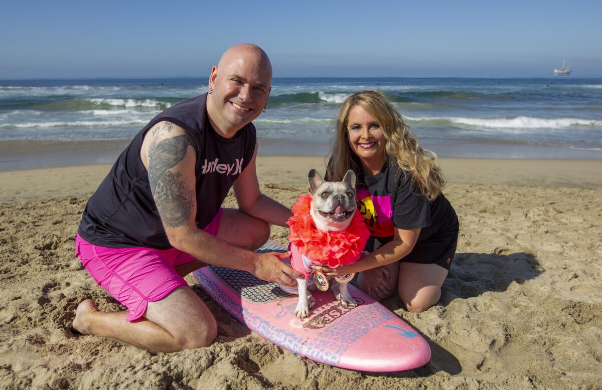 Dan and Amy Nykolayko of Newport Beach pose with their French bulldog Cherie, who won the World Dog Surfing Championships this month.