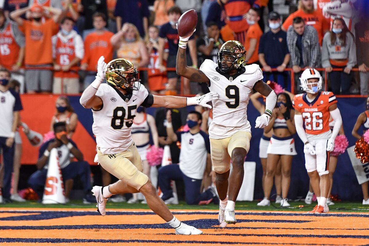 Wake Forest wide receiver A.T. Perry (9) celebrates with tight end Blake Whiteheart (85) after scoring a touchdown during overtime of an NCAA college football game against Syracuse in Syracuse, N.Y., Saturday, Oct. 9, 2021. Wake Forest beat Syracuse 40-37. (AP Photo/Adrian Kraus)