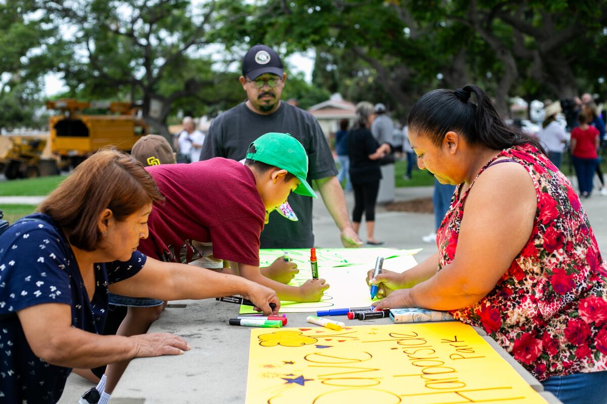 Michelle Rodriguez, right, and her family make posters before marching to Harborside Park on Oxford Street.