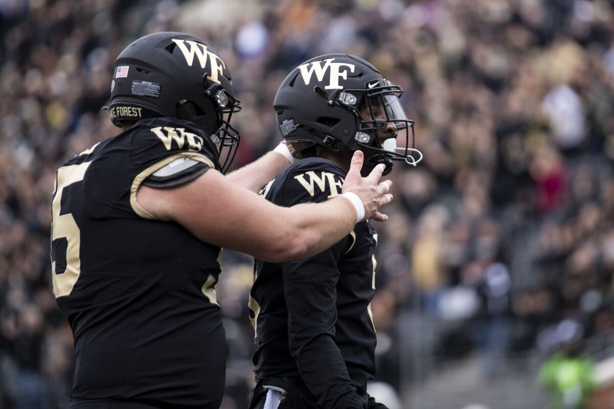 Wake Forest offensive lineman Michael Jurgens looks to embrace wide receiver Jaquarii Roberson.