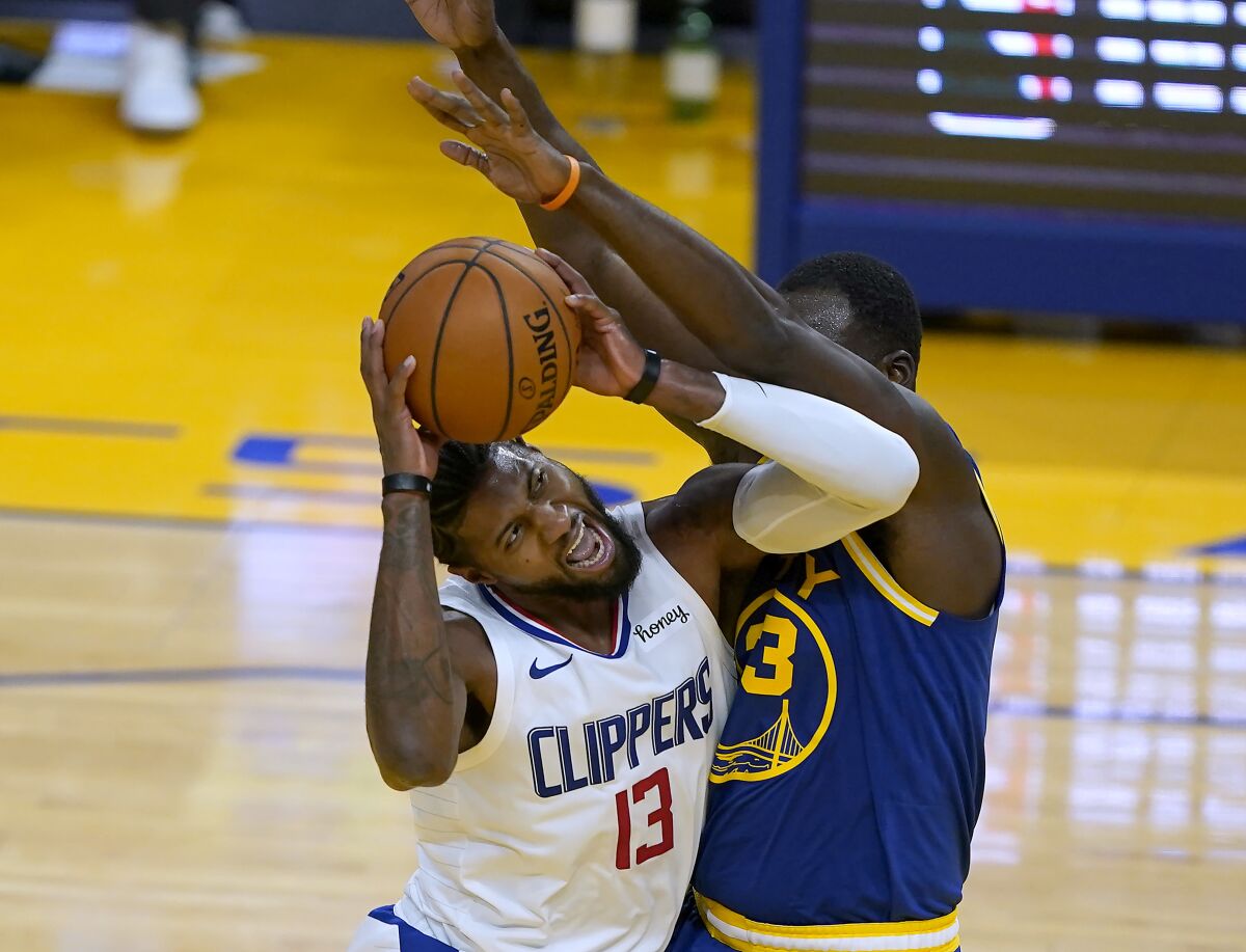 Clippers forward Paul George is fouled by Warriors forward Draymond Green.