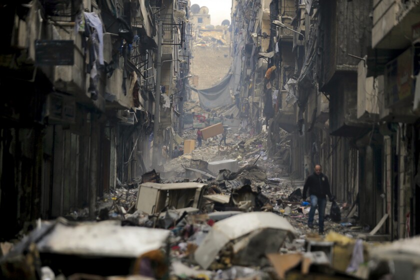 FILE - Residents walk through the destruction of the once rebel-held Salaheddine neighborhood in the eastern Aleppo, Syria, Jan. 20, 2017. The United Nations said the first 10 years of Syria’s conflict, which began in 2011, killed more than 300,000 civilians. The report released Tuesday, June 28, 2022, by the U.N. Human Rights Office is the highest yet estimate of conflict-related civilian deaths in the country. Syria's conflict began with anti-government protests that broke out in March 2011 in different parts of Syria, demanding democratic reforms following Arab Spring protests across the Middle East. (AP Photo/Hassan Ammar, File)