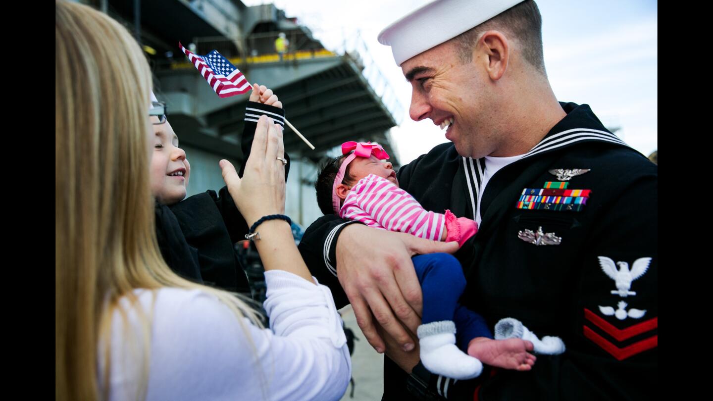 Petty Officer Josh Labbe meets his 2 1/2-day-old daughter as his wife, Ashli Labbe, and son, Brodin Labbe, 3, greet him after disembarking from the Peleliu.
