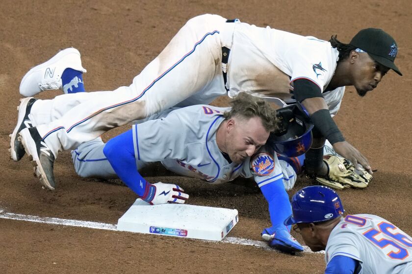 New York Mets' Brandon Nimmo, bottom left, collides with Miami Marlins third baseman Jean Segura, top, as he is safe at third on a single hit by Starling Marte (not shown) during the sixth inning of an opening day baseball game, Thursday, March 30, 2023, in Miami. (AP Photo/Lynne Sladky)