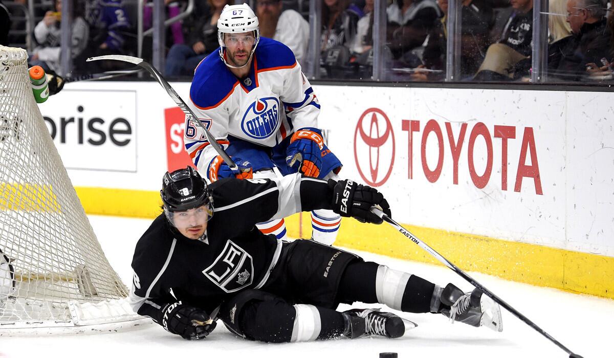 Kings defenseman Drew Doughty falls as he passes the puck under pressure from Oilers left wing Benoit Pouliot during the Kings', 8-2, victory over the Oilers on Thursday.