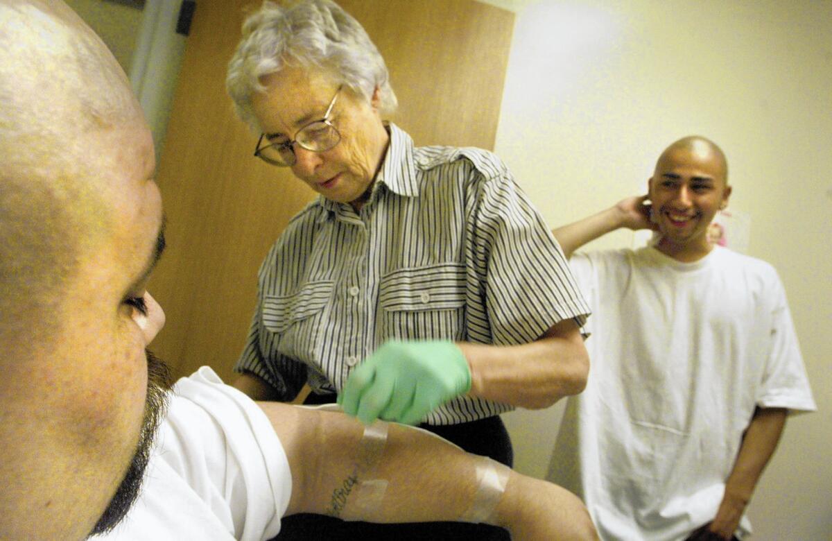 Sister June Wilkerson, center, bandages a man in the process of getting a tattoo removed in 2000. Wilkerson began the removal program in 1998 and helped hundreds of people erase the marks of their gang affiliations.