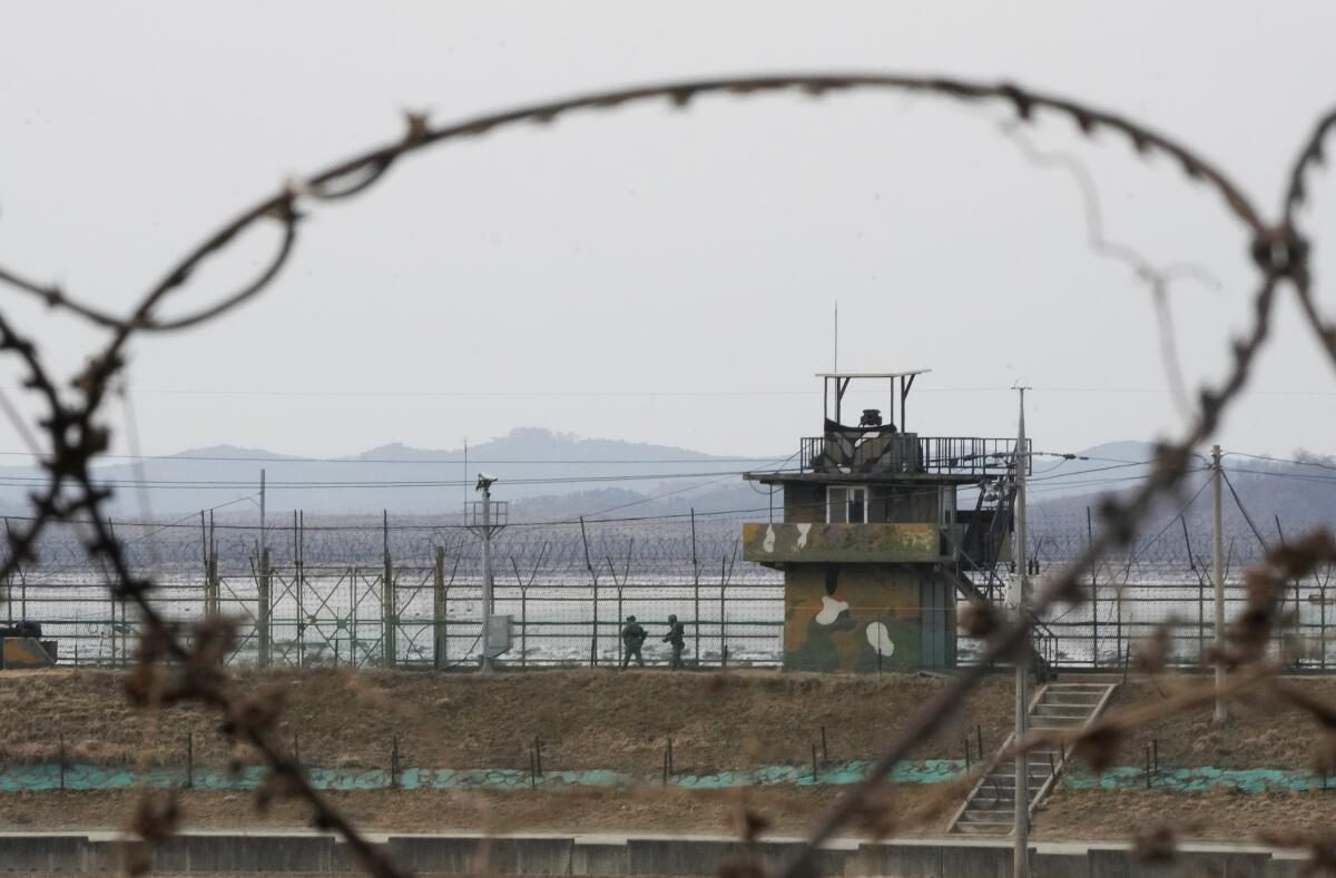 View through barbed wire of South Korean soldiers on patrol