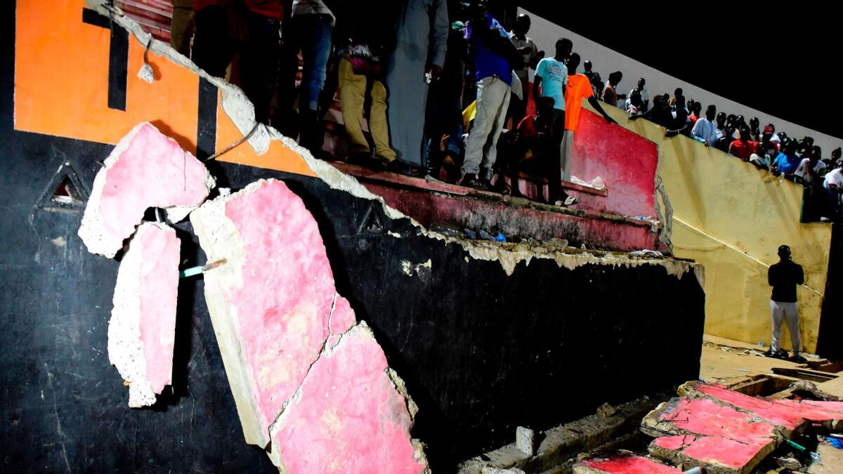 Soccer fans stand near a collapsed wall at Demba Diop stadium in Dakar, Senegal.
