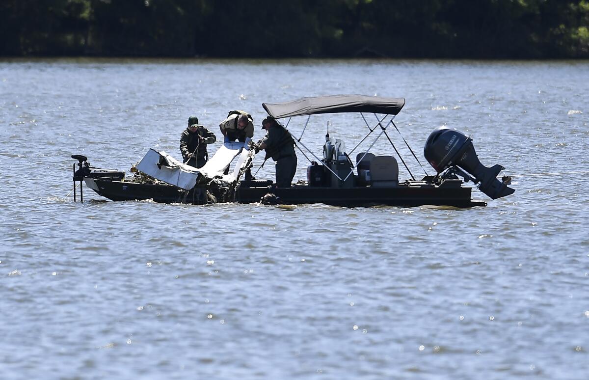 Emergency personnel are on a boat and remove debris from a plane crash in Percy Priest Lake