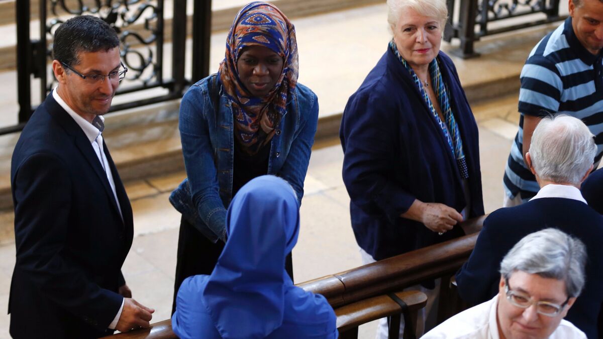 A Muslim woman shakes hands with a nun during a Mass in tribute to priest Jacques Hamel in the Rouen Cathedral.