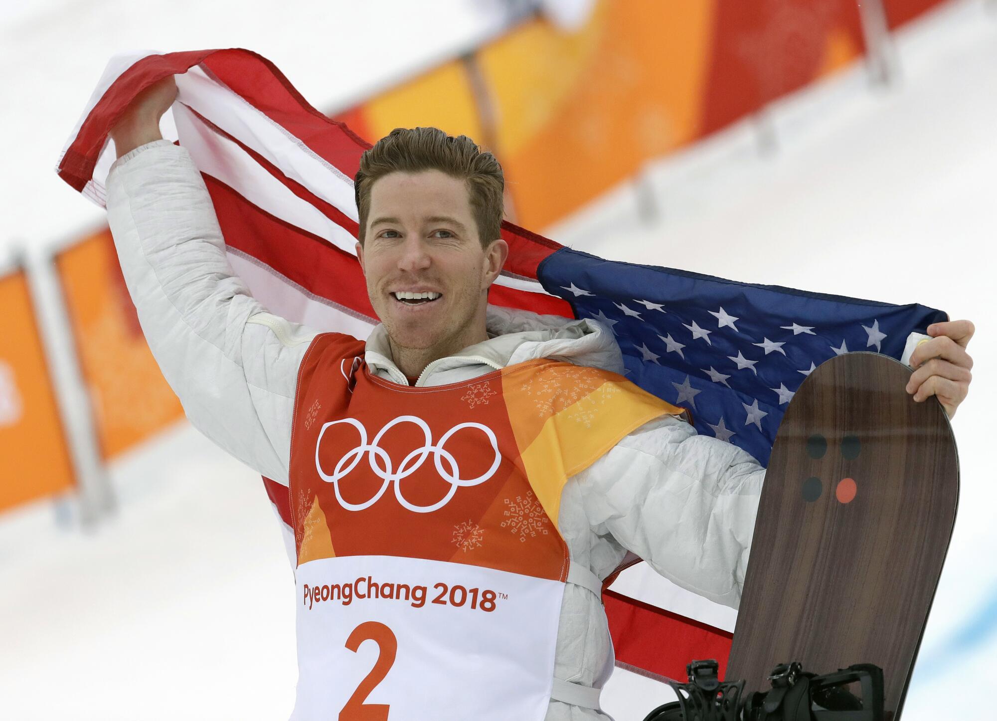 Shaun White holds a U.S. flag at the 2018 Olympics.